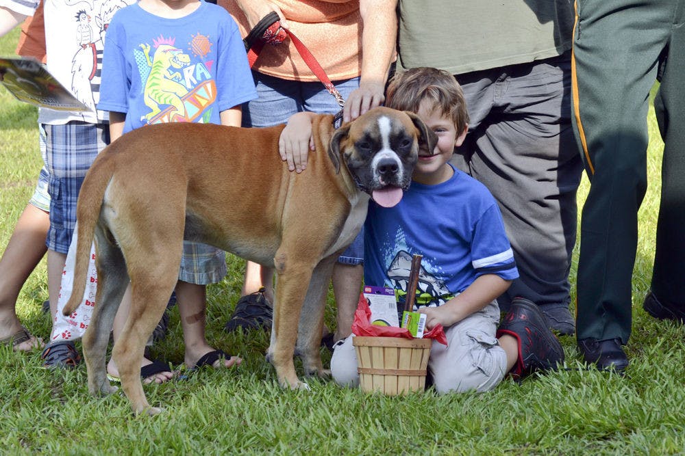 <p>Daniel Roth, 6, snuggles his newly adopted boxer, Barney Collier, during a group photo of the “Paws on Parole” graduates. The dogs were named after characters in the movie Mission Impossible as the theme for their graduating class was "Mission Pawsible." Roth was able to take Barney home after the ceremony.</p>