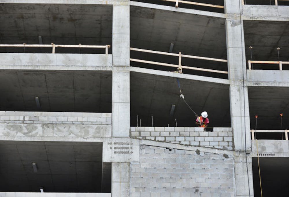 <p>A construction worker lays bricks while working on a new parking garage Wednesday afternoon behind Roberts’ Stadium Club on University Avenue. It should be completed in August.</p>
<div>&nbsp;</div>