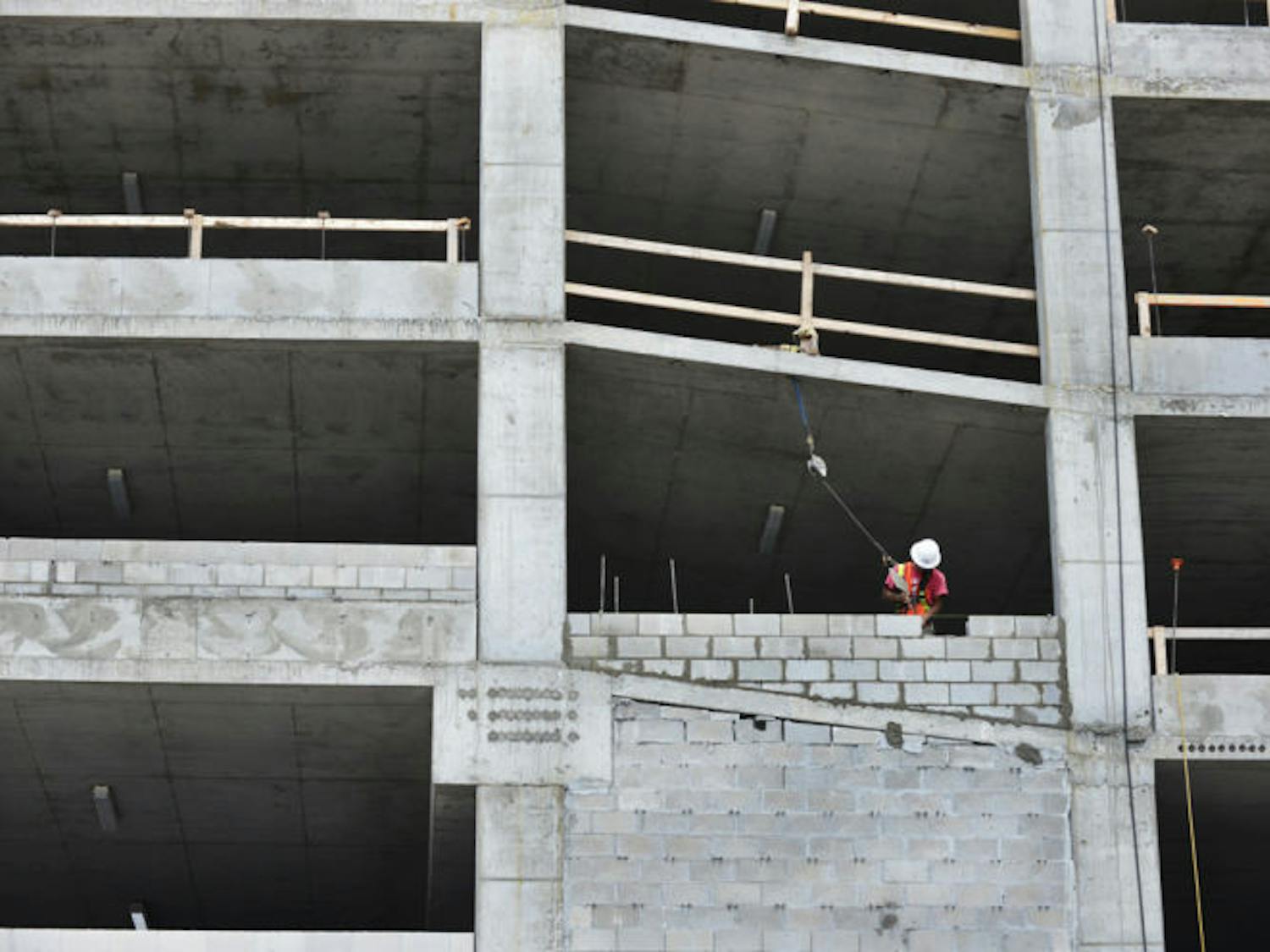 A construction worker lays bricks while working on a new parking garage Wednesday afternoon behind Roberts’ Stadium Club on University Avenue. It should be completed in August.
&nbsp;