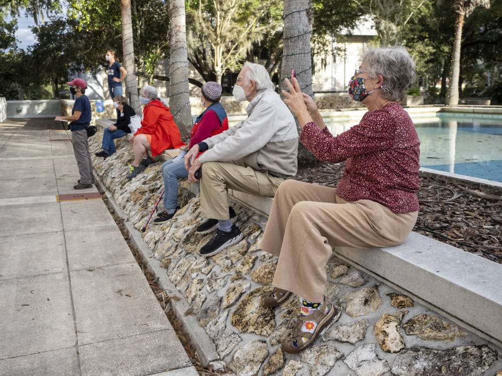 A group of people are seen listening to speakers from the Blue Wave Coalition in Alachua County, who organized a Protect the Results rally held at the Alachua City Hall on Wednesday, Nov. 4, 2020. (Emily Felts/Alligator Staff)
