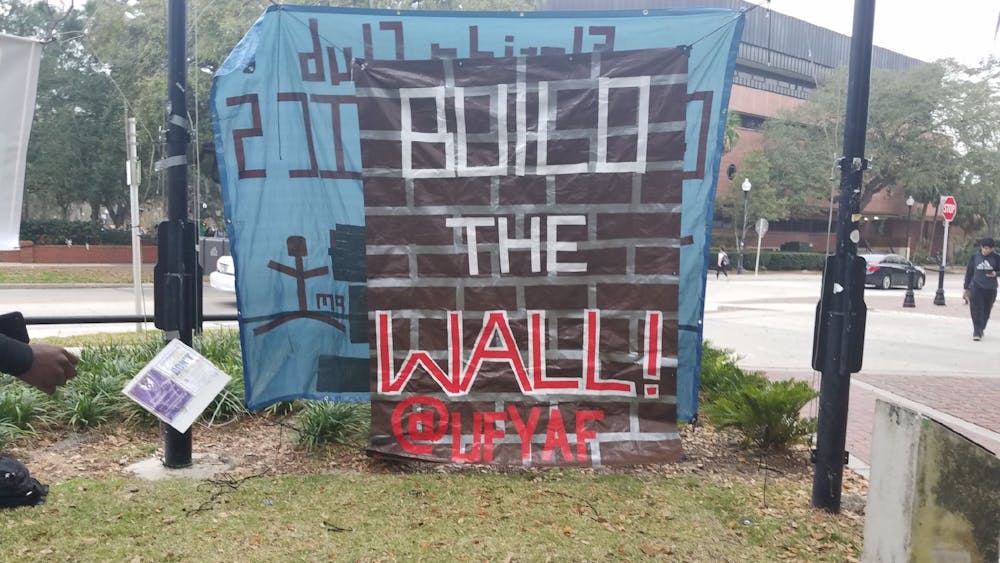 <p>UF’s chapter of Young Americans for Freedom’s banner hangs on the Plaza of the Americas. The “Build the Wall” banner was removed three times.</p>