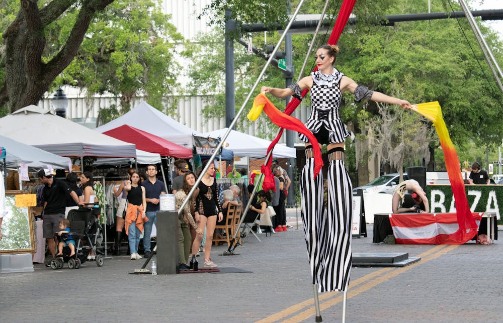 <p>Griffin Wulf, a stilts performer, walks around the heart of Downtown Gainesville at the Bazar À La Carte Saturday, March 25, 2023.</p>