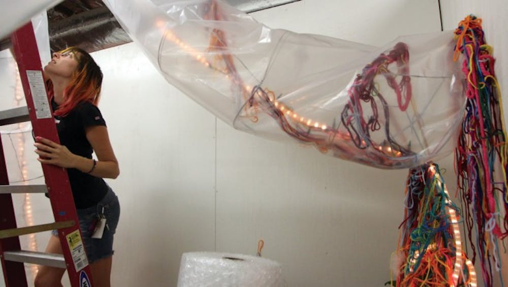<p>Second-year printmaking graduate student Jessica Normington, 26, works on an installation for GRADhaus. The installation represents neurons working inside her head.</p>