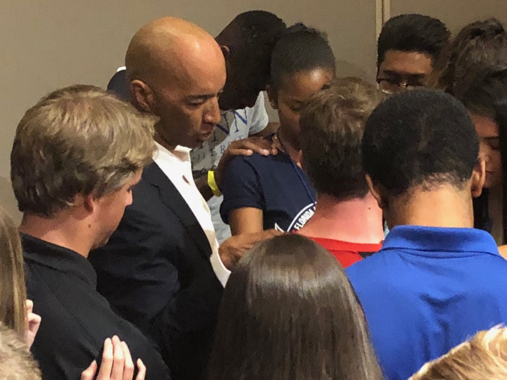 Byron Pitts, 57, and about 30 people form a circle around Santa Fe College student Walker, 27, and pray.