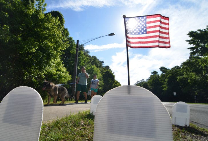 Passers by view thousands of paper tomb stones representing the U.S. Department of Defense Iraq and Afghanistan casualties on NW 8th Avenue on Monday in Gainesville, Fla.