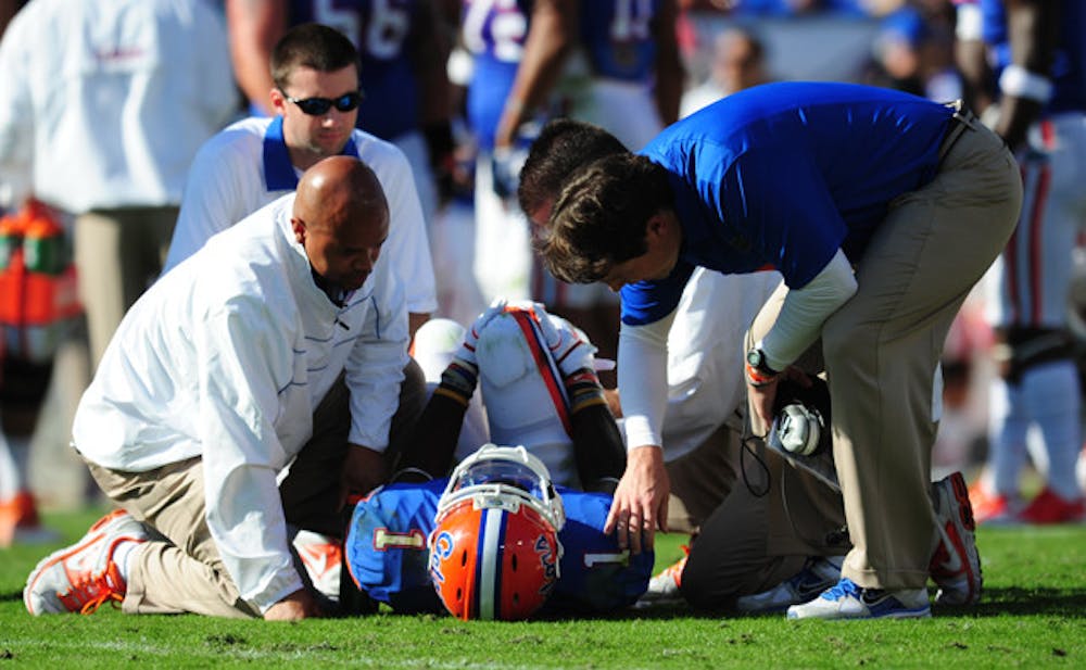 <p>Running back Chris Rainey (1) is attended to by multiple trainers during Saturday’s loss to Georgia while coach Will Muschamp (right) looks on. Rainey injured his right ankle early in the first quarter but returned in the second quarter.</p>