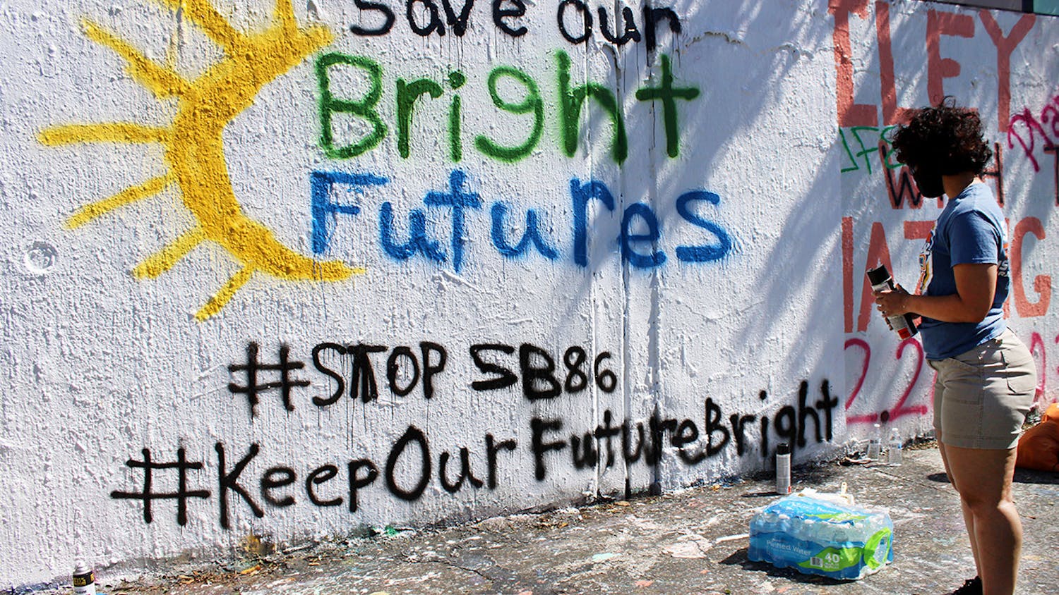 Alondra Arce, 20, a sustainability sophomore, looks at the “Save Our Bright Futures” mural she helped paint on the side of 34th Street in Gainesville on Sunday, March 7, 2021.