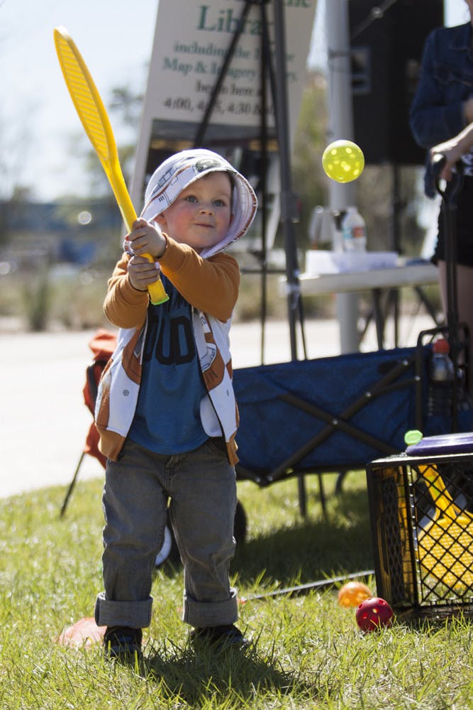 Killian Pennell, 3, plays with a Wiffle ball at the YMCA booth during Active Streets Gainesville at Depot Park on Sunday. Killian's dad, Kyle Pennell, said this is Killian's second time coming to Active Streets Gainesville. 