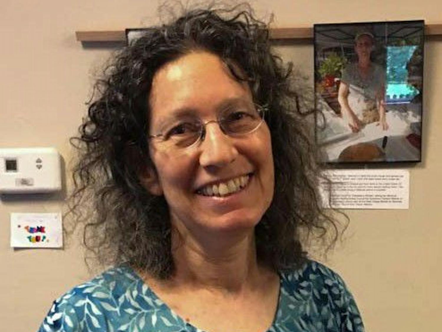 Renee Hoffinger, 65, stands by her photos at the "Immigrants of Gainesville" exhibit.