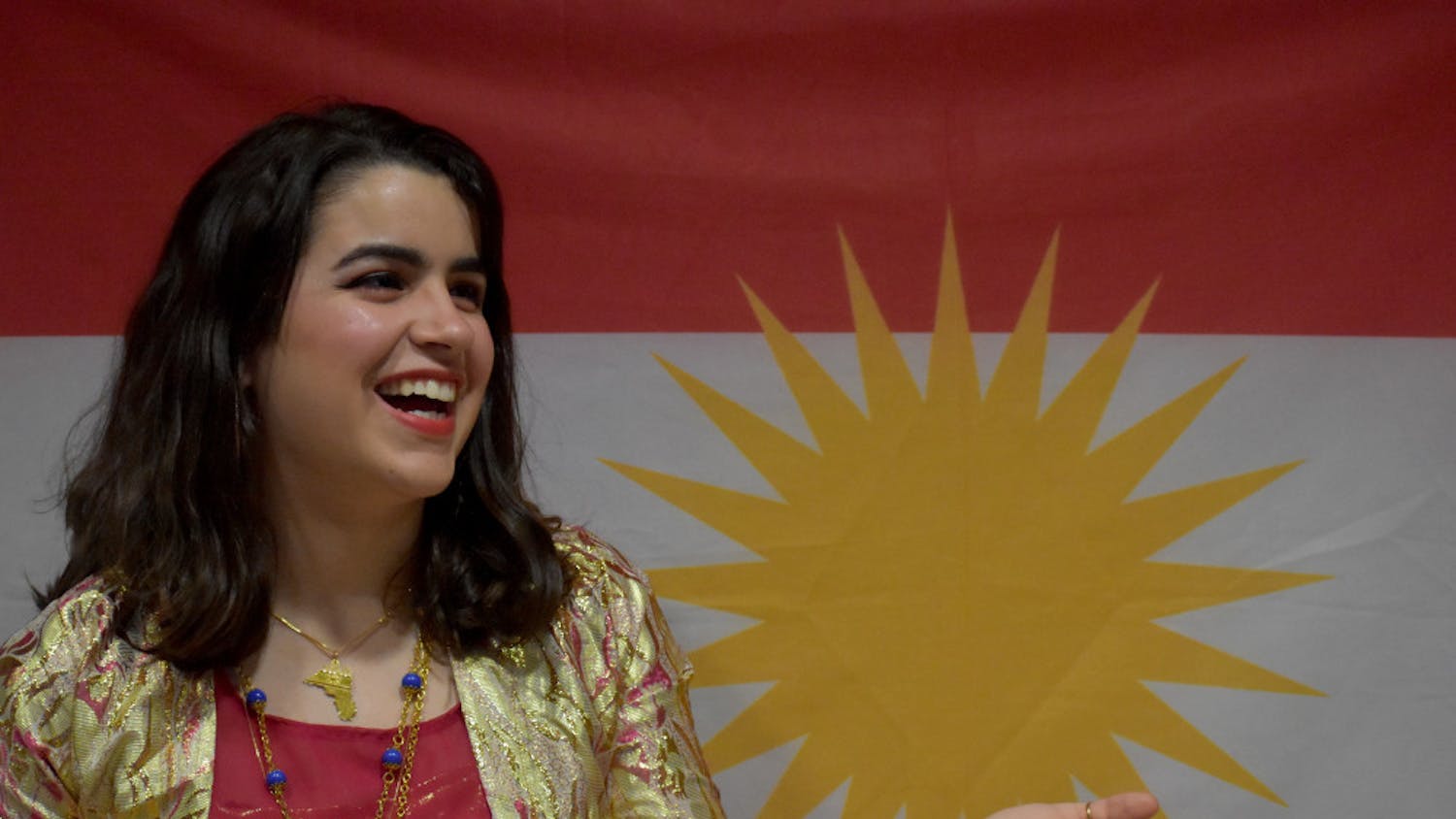 Sara Zandy, 20, representing her culture wearing a jily kurdy in front of the Kurdish flag.