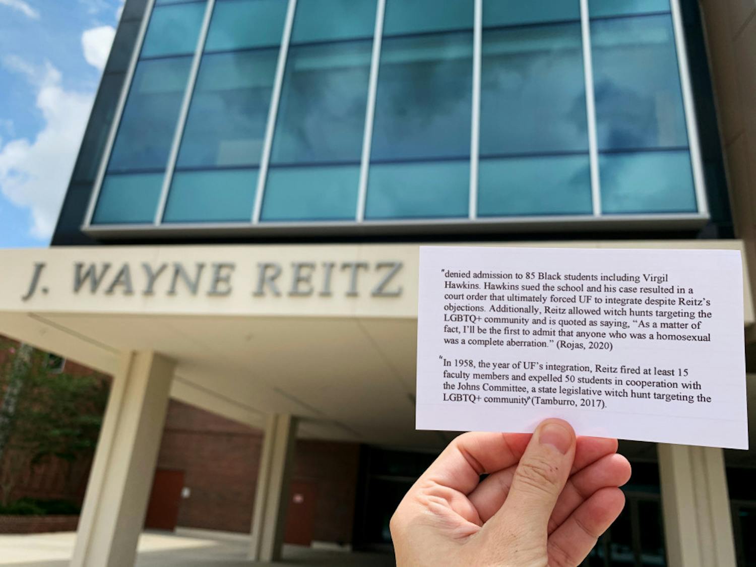 Shelby Boehm, a 28-year-old UF English education Ph.D. student, holds up a piece of paper highlighting J. Wayne Reitz' controversial history with the Reitz Union sign visible in the background. She got the information from Anthony Rojas' petition, and said she took the photos while walking around campus because she wanted to do her part in spreading the information to other students and faculty. The photos were posted to Instagram and got hundreds of likes. 