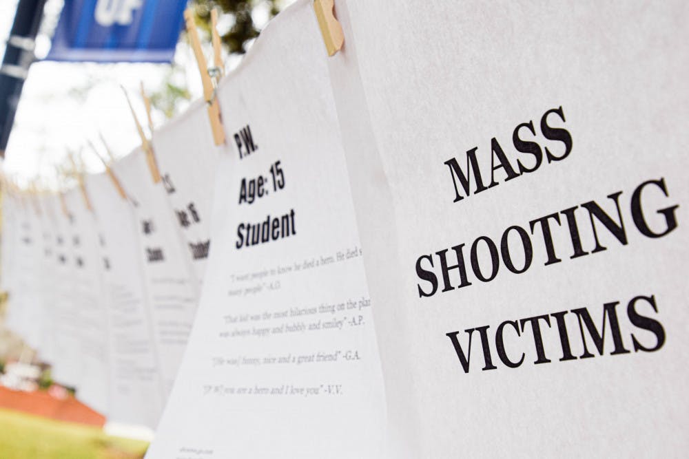 March For Our Lives Gainesville pins up pieces of paper with information about people who died in various mass shootings, such as their name, age and what they were like as told by loved ones.