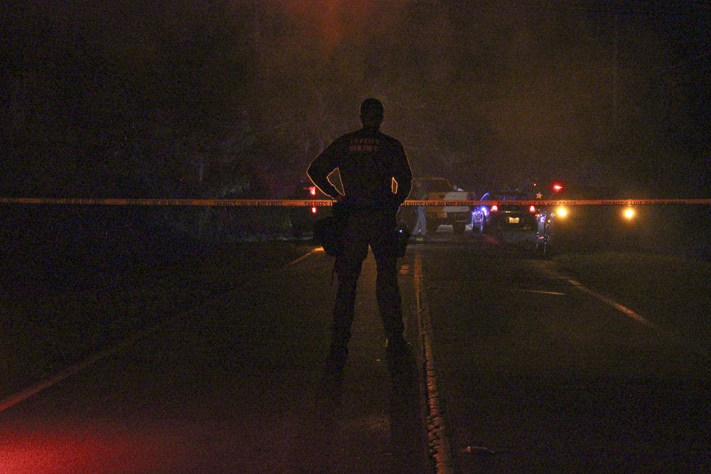 An officer with the Alachua County Sheriff’s office patrols the crime scene on Southeast Wacahoota Road on Tuesday night.