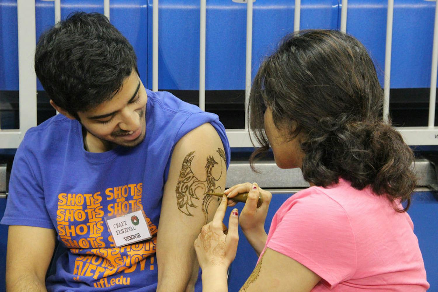 Jeena Kar (right), a 22-year-old UF arts in medicine graduate, draws a henna tattoo on UF nutrition student Tobin Chakkala's arm on Dec. 6, 2015.