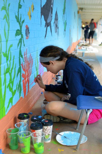 Katie Weiser, a 19-year-old UF mechanical engineering sophomore, puts the finishing touches on a mural at the Sidney Lanier Center on Sunday.&nbsp;