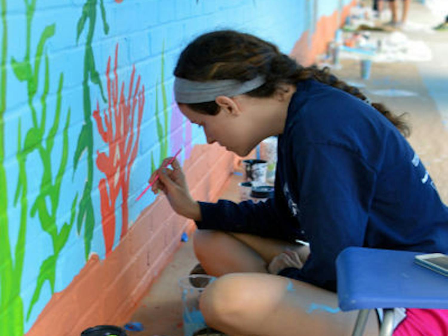 Katie Weiser, a 19-year-old UF mechanical engineering sophomore, puts the finishing touches on a mural at the Sidney Lanier Center on Sunday.&nbsp;