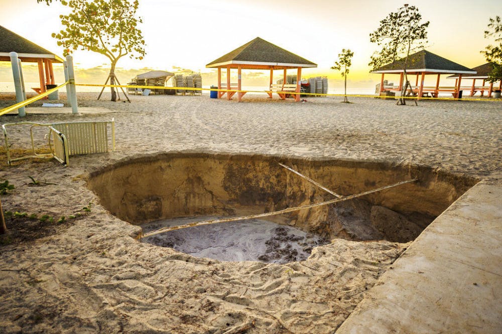 A sinkhole is surrounded by police tape after it appeared when a powerful magnitude 7.7 earthquake struck in the Caribbean Sea between Jamaica and eastern Cuba, at Public Beach on West Bay, Grand Cayman, Tuesday, Jan. 28, 2020. The quake also hit the Cayman Islands, leaving cracked roads and what appeared to be sewage spilling from cracked mains. There were no immediate reports of deaths, injuries or more severe damage. (Taneos Ramsay/Cayman Compass via AP)