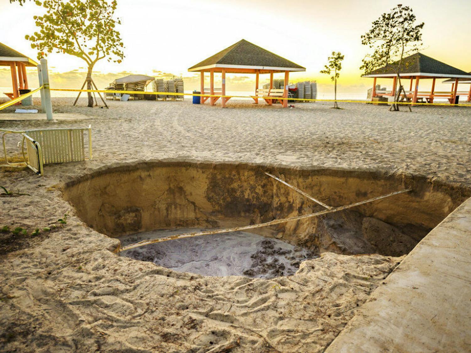 A sinkhole is surrounded by police tape after it appeared when a powerful magnitude 7.7 earthquake struck in the Caribbean Sea between Jamaica and eastern Cuba, at Public Beach on West Bay, Grand Cayman, Tuesday, Jan. 28, 2020. The quake also hit the Cayman Islands, leaving cracked roads and what appeared to be sewage spilling from cracked mains. There were no immediate reports of deaths, injuries or more severe damage. (Taneos Ramsay/Cayman Compass via AP)