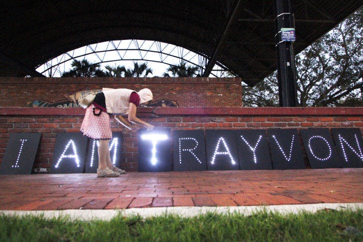 Gainesville resident Nancy Jones, 50, repositions a light display created by Occupy Gainesville to commemorate the anniversary of Trayvon Martin’s death.