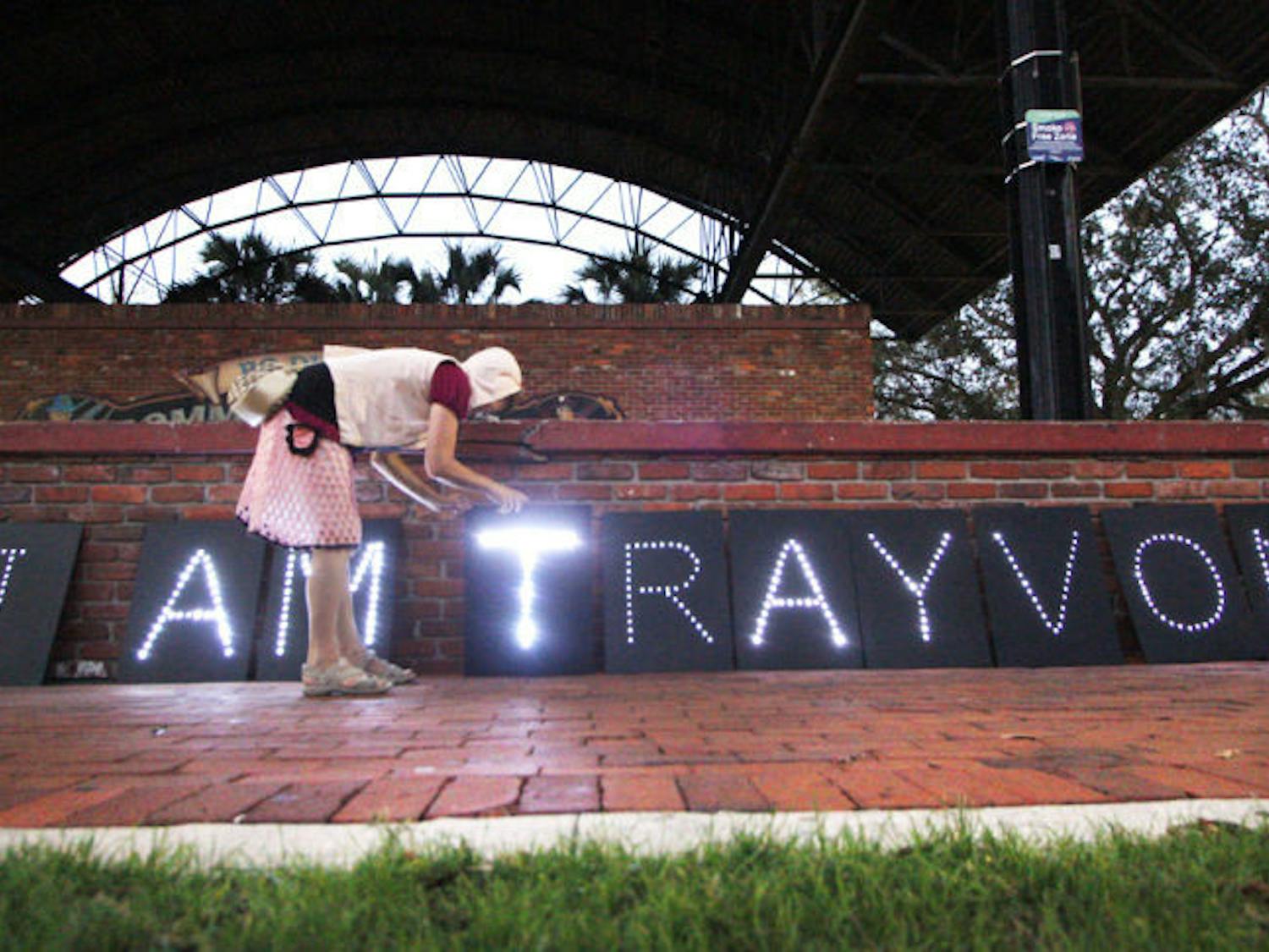 Gainesville resident Nancy Jones, 50, repositions a light display created by Occupy Gainesville to commemorate the anniversary of Trayvon Martin’s death.