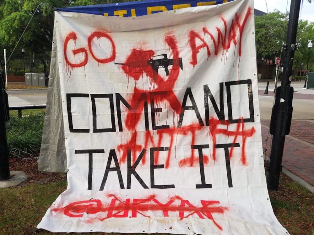 <p dir="ltr"><span>UF’s Young Americans for Freedom gun rights banner hangs on Plaza of the Americas Saturday morning after being spray painted with the words “Go away” by an unknown vandalist.</span></p>