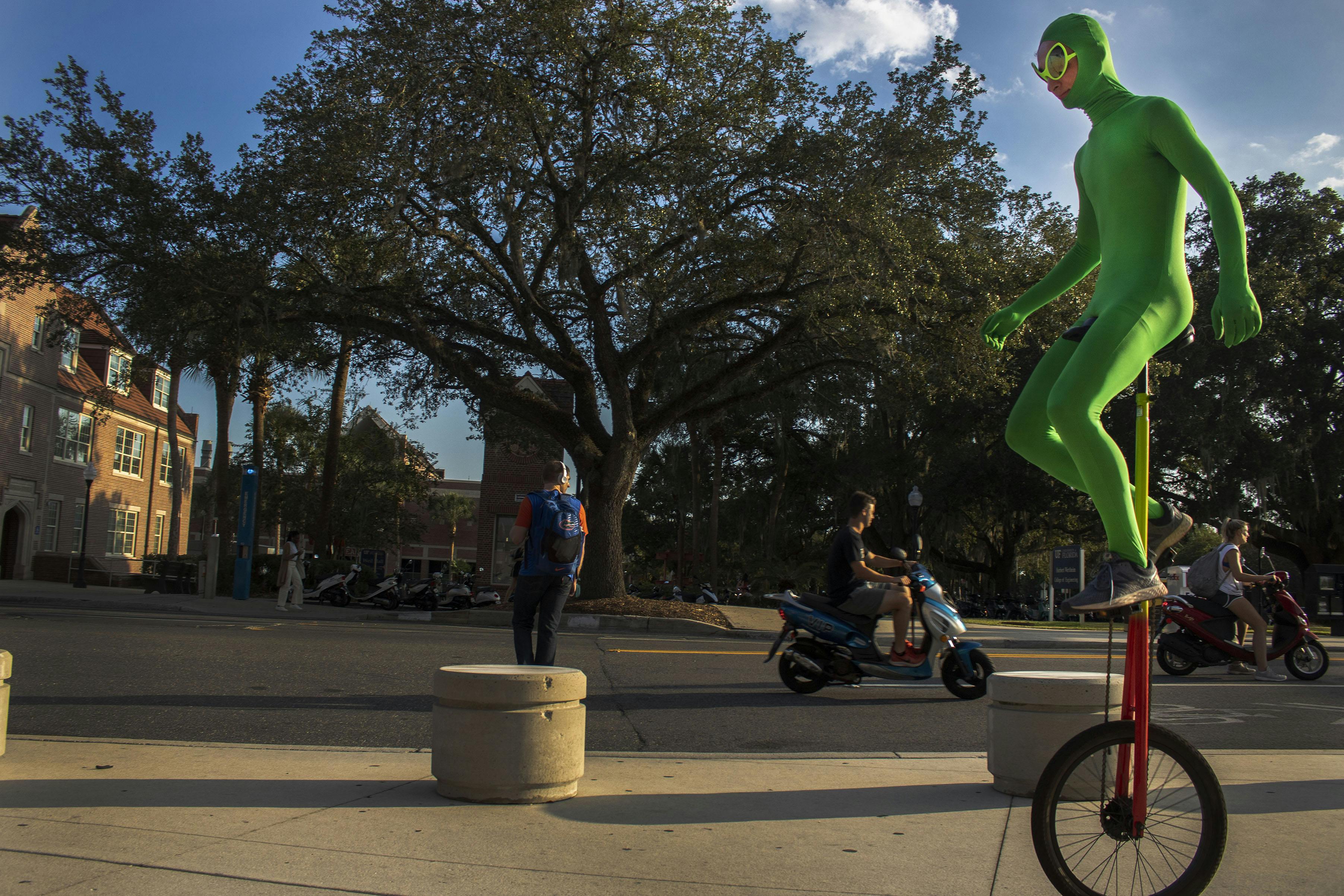 Ethan Gamble, 17-year-old Gainesville High student, rides his unicycle down Stadium Road while wearing his green alien outfit. Gamble said he first started by riding around the bus loop at JJ Finley Elementary school. “You just have to practice,” Gamble said. “Until you get the feel of it.” 