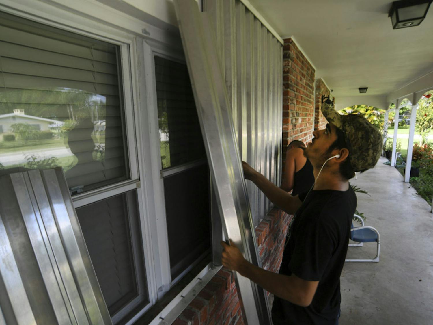 Richard Henson (foreground) and his uncle, Peter Henson, prepare their grandmother's house Thursday, Aug. 29, 2019, where she lives on Greenwood Drive in Fort Pierce, Fla., for the arrival of Hurricane Dorian. (Eric Hasert/TCPalm.com via AP)