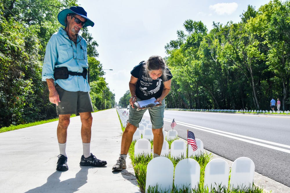 From left: David Gold accompanies his wife, Judy Gold, as she records all of the tombstones with flags and/or flowers left behind. Each year, she makes sure the tombstones of veterans with connections to the area are marked with flags so they can be found easily.
