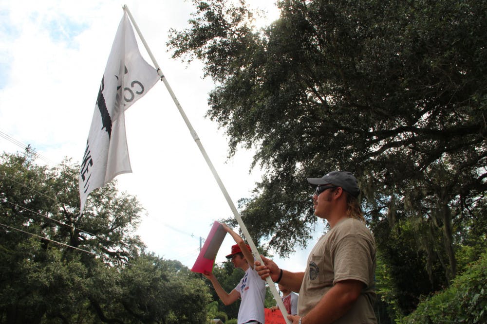 Libertarian party member Chris Rose II (right), 29, waves flag with the words "Come and Get It" printed next to a firearm with to 21-year-old Taylor Wyatt Foland (left). &nbsp;The two protested across the street from the Gainesville Women's Club during the March For Our Lives panel.