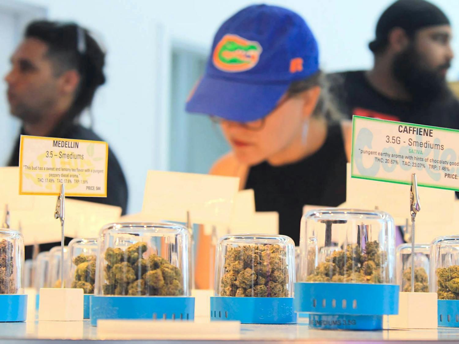 Customers gather around the &quot;bud bar,&quot; a round table showcasing dozens of cannabis strains at Cookies on Saturday, July 1, 2023. ﻿
