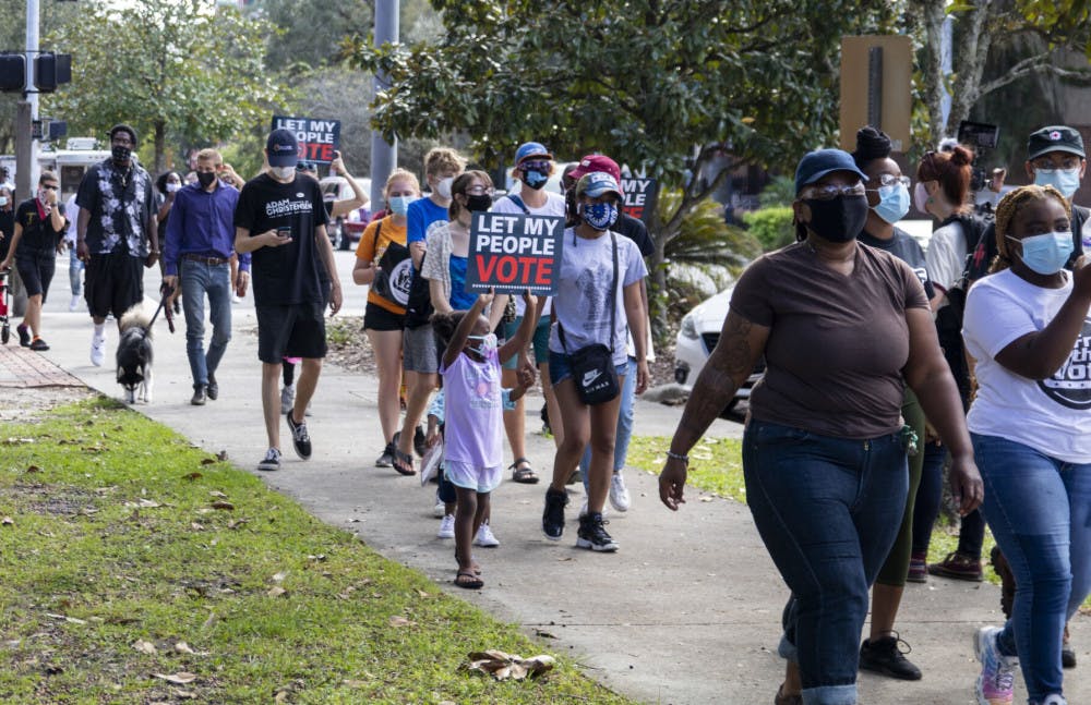 People are seen holding “Let My People Vote” signs at the "Free the Vote" rally while walking away from Bo Diddley Plaza on Saturday, Oct. 24, 2020.