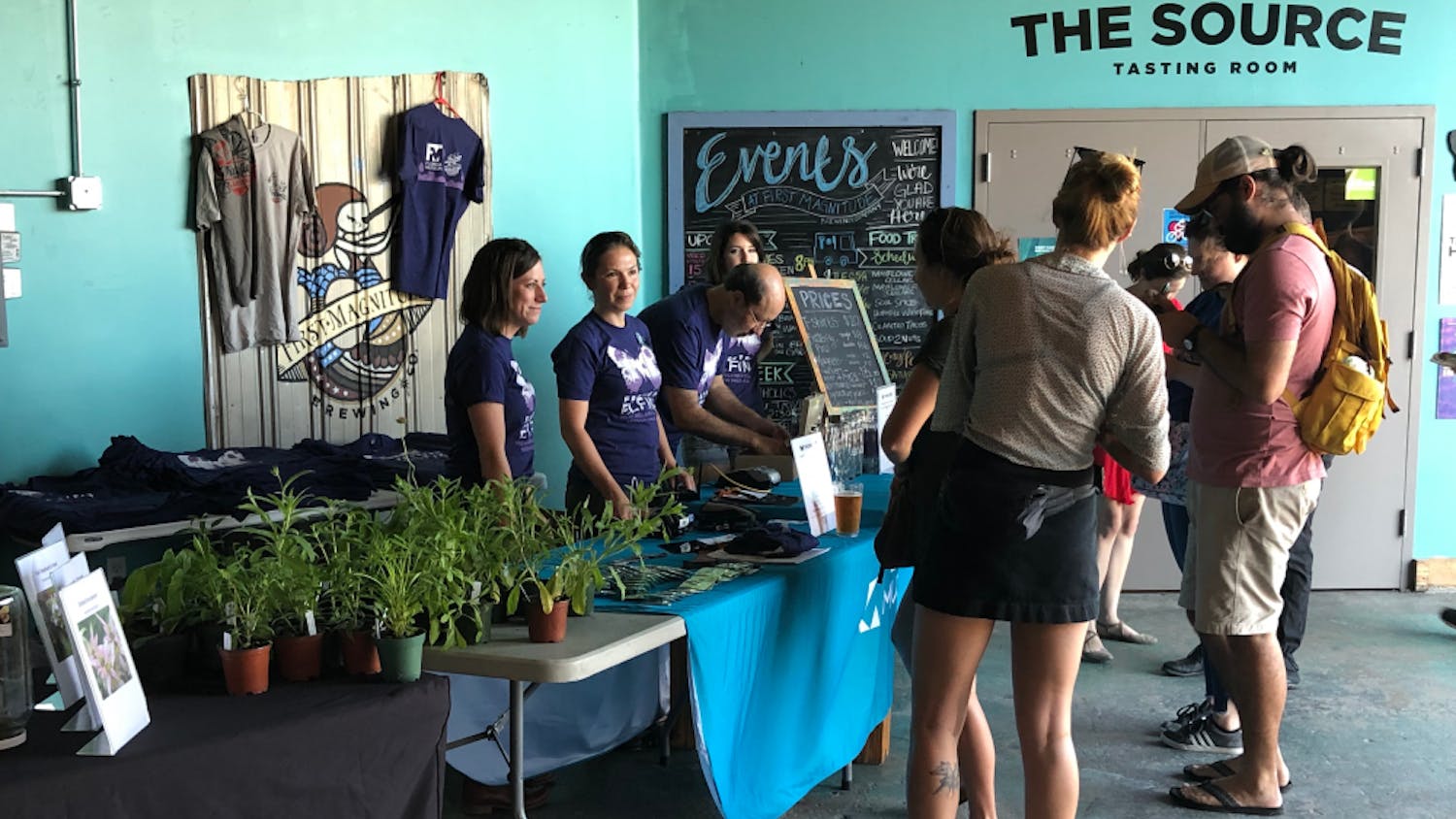 Attendees at First Magnitude's event line up to donate and purchase t-shirts, pins and glasses to support the Frosted Elfin butterfly. 