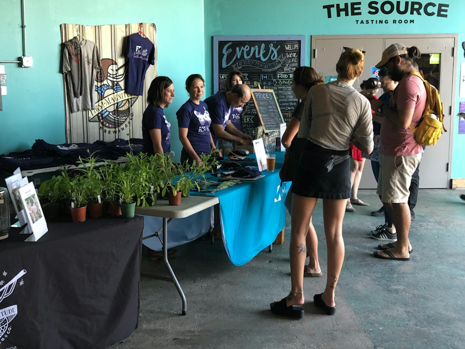 Attendees at First Magnitude's event line up to donate and purchase t-shirts, pins and glasses to support the Frosted Elfin butterfly. 