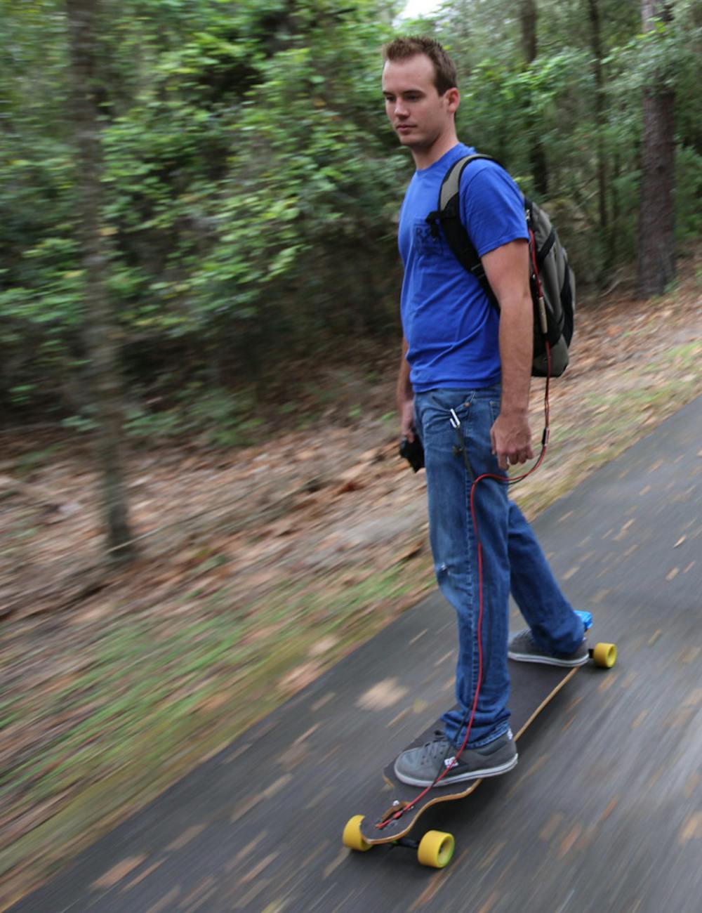 <p>Aaron King, UF alumnus and founder of RedRock Board Shop, rides down the Gainesville-Hawthorne State Trail on one of his electric longboards Oct. 9. The electronics for a board cost $300.</p>