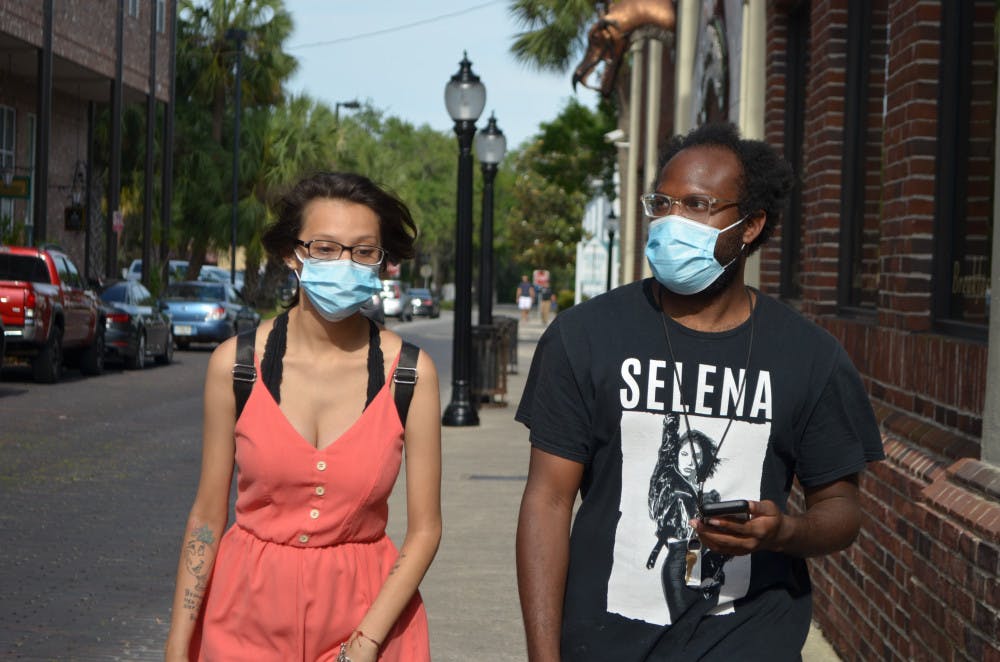 Denise Garcia and Jeffery Davis wear face masks in downtown Gainesville. The commission voted Tuesday to end the face mask requirement in its emergency order. 