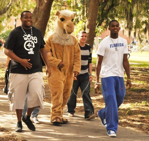 Junior Chris Haugabook, 21, sophomore Francisco Hidalgo, 19, and sophomore Eddie Lovett, 19, walk with Humpty, the mascot of Phi Beta Sigma Fraternity, to Turlington Plaza to promote their toy drive.
