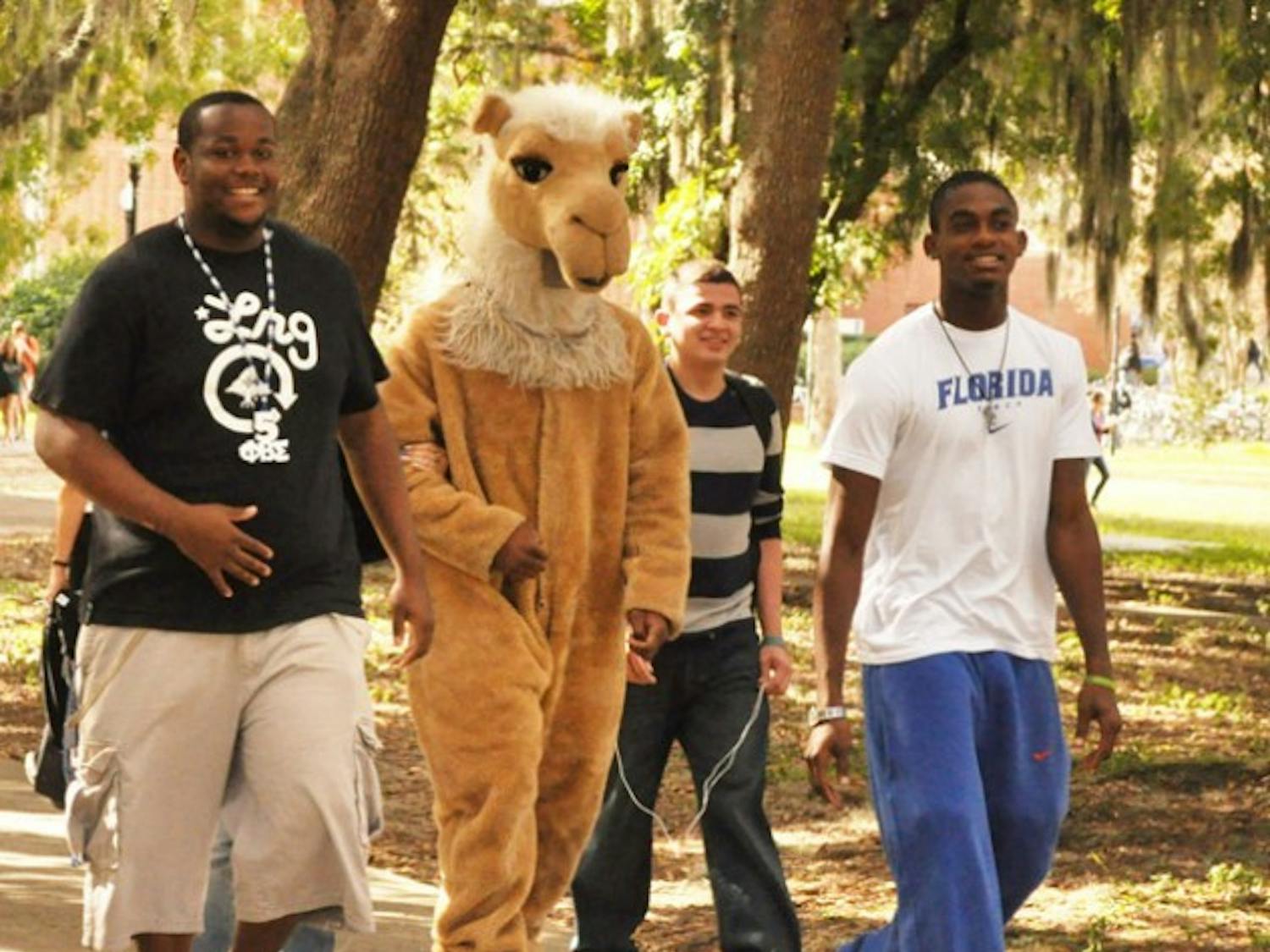Junior Chris Haugabook, 21, sophomore Francisco Hidalgo, 19, and sophomore Eddie Lovett, 19, walk with Humpty, the mascot of Phi Beta Sigma Fraternity, to Turlington Plaza to promote their toy drive.