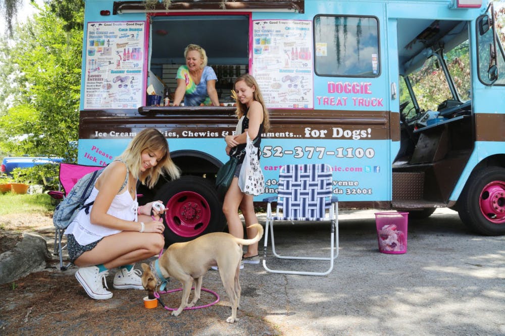 From left, UF animal sciences seniors Marien Armenteros, 23, and Sarah Flanders, 21, feed doggy ice cream to Toby, which was purchased from Paige Anderson, 50, at the Earth Pets Doggie Treat Truck at the Earth Pets Woofstock 2014 event on Saturday.