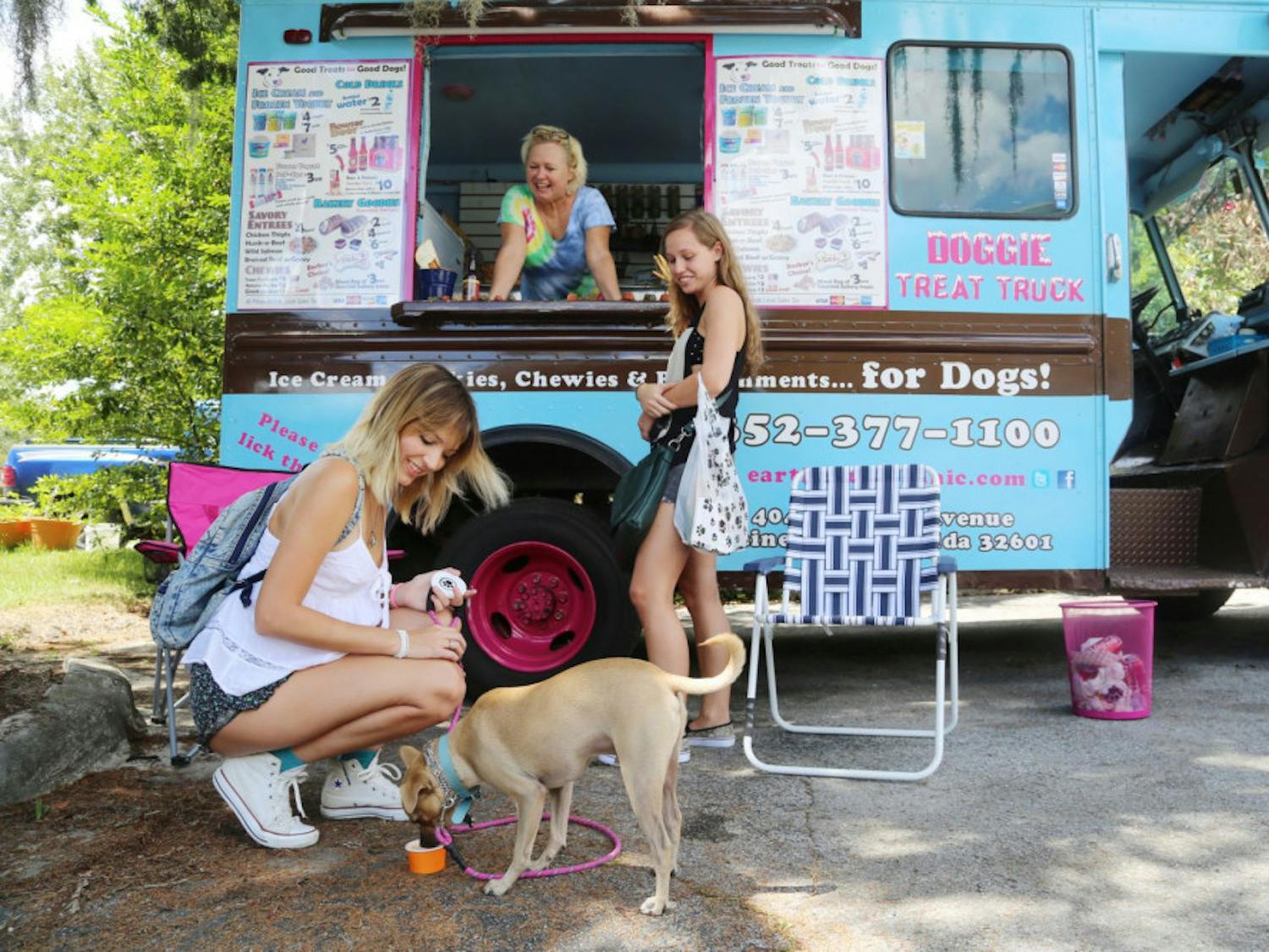 From left, UF animal sciences seniors Marien Armenteros, 23, and Sarah Flanders, 21, feed doggy ice cream to Toby, which was purchased from Paige Anderson, 50, at the Earth Pets Doggie Treat Truck at the Earth Pets Woofstock 2014 event on Saturday.