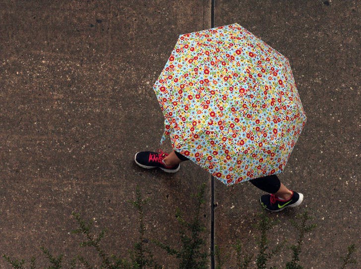 A Nike-wearing umbrella holder takes strides down Stadium Road in the rain on Monday.