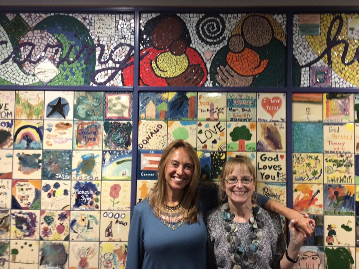 Artist Lee Ann Dodson poses for a photo with colleague Mary Rockwood Lane, a UF nursing professor, in front of the “Healing Wall,” a collection of thousands of colored tiles painted by patients, staff members, family members and friends.