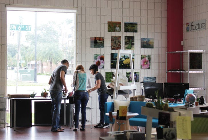Customer experience employee Brittany Ferguson assists visitors at Fracture on Monday afternoon. The startup, located at 112 SW 6th St., has recently been featured in a national TV spot.