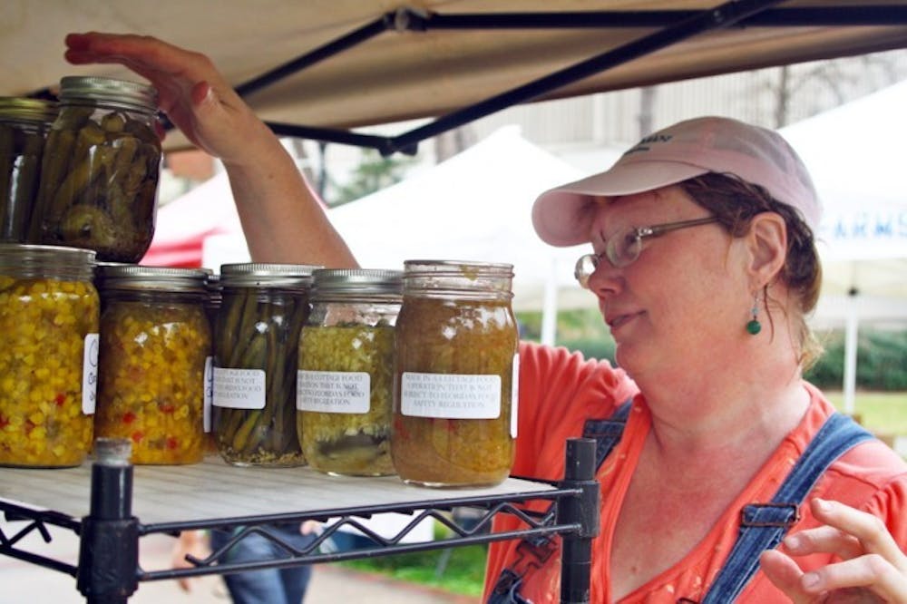 <p>Robin Stahr sets up her table for the farmers market on the North Lawn near the Reitz Union on Friday. Stahr's business sells scones, jams, pickled vegetables, local honey and more.</p>