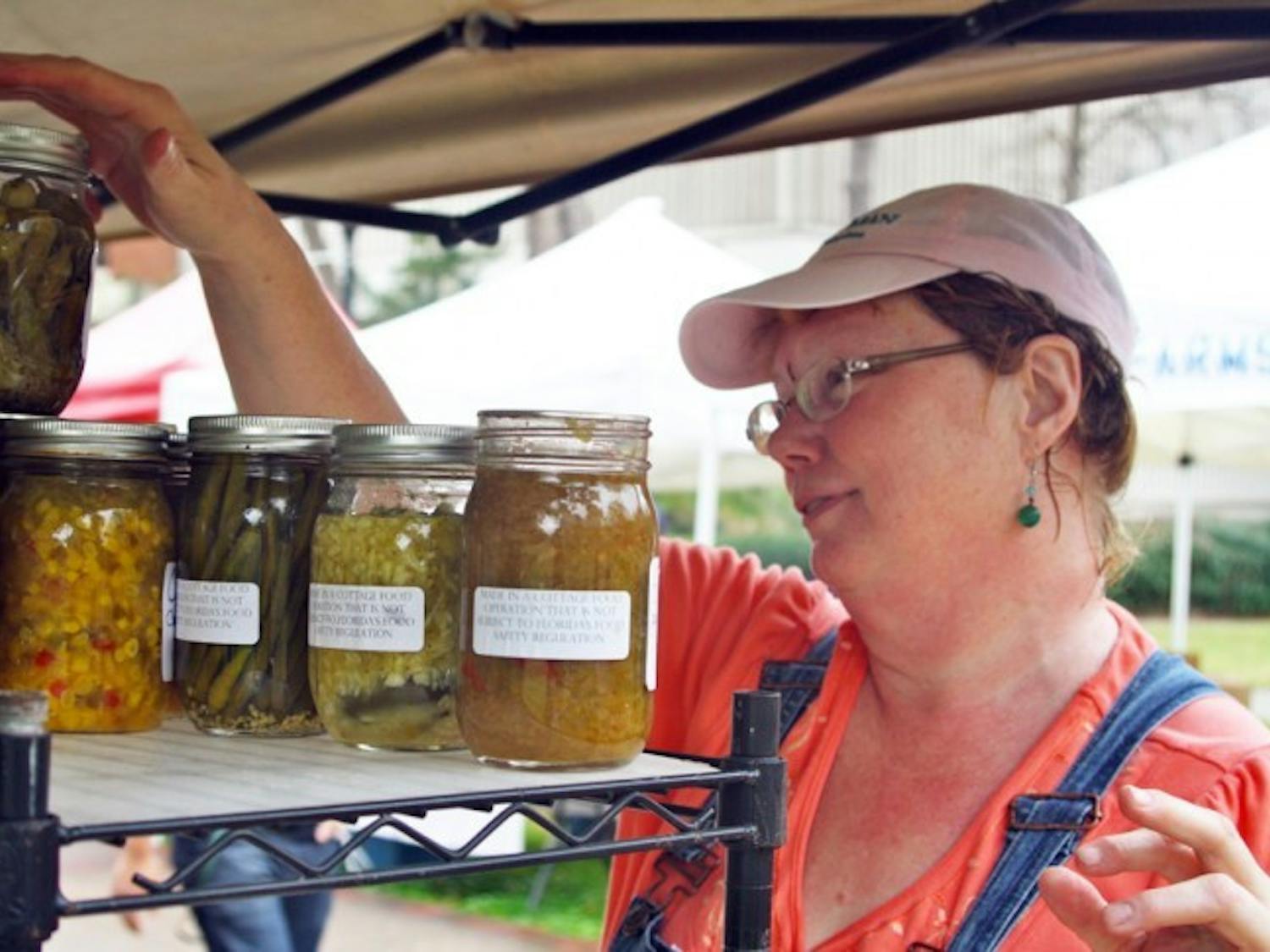 Robin Stahr sets up her table for the farmers market on the North Lawn near the Reitz Union on Friday. Stahr's business sells scones, jams, pickled vegetables, local honey and more.