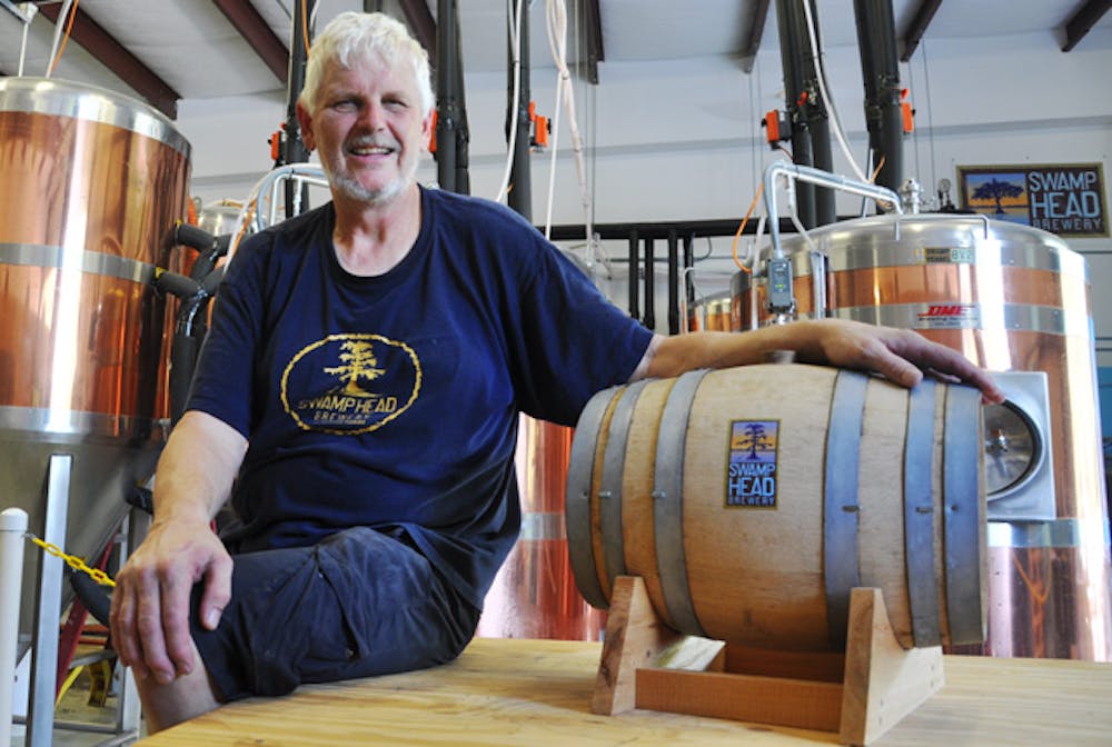 <p>Head brewer Craig Birkmaier poses next to a cask of beer at Swamp Head Brewery on Thursday. He recovered part of a batch of beer Monday after power was cut for more than an hour.</p>