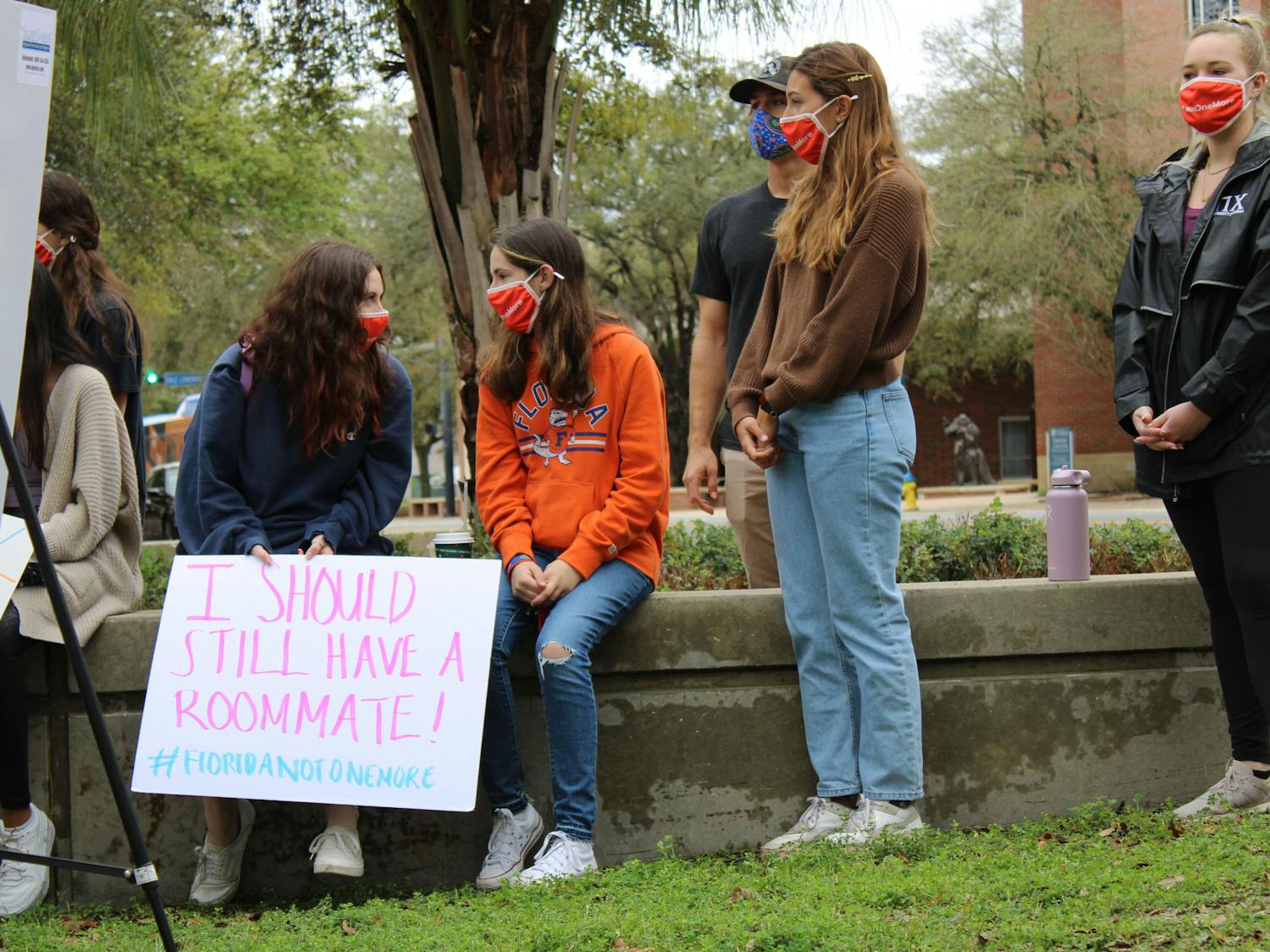 Sydney Kaskin (left), 19, a neuroscience freshman and former roommate of Sophia Lambert holds a sign that says "I should still have a roommate!" as she speaks with another member of the Florida Not One More student group during a press conference on Wednesday, March 3, 2021. The press conference was held by two attorneys representing the families of Sophia Lambert and Maggie Paxton in two wrongful death lawsuits that were recently filed.