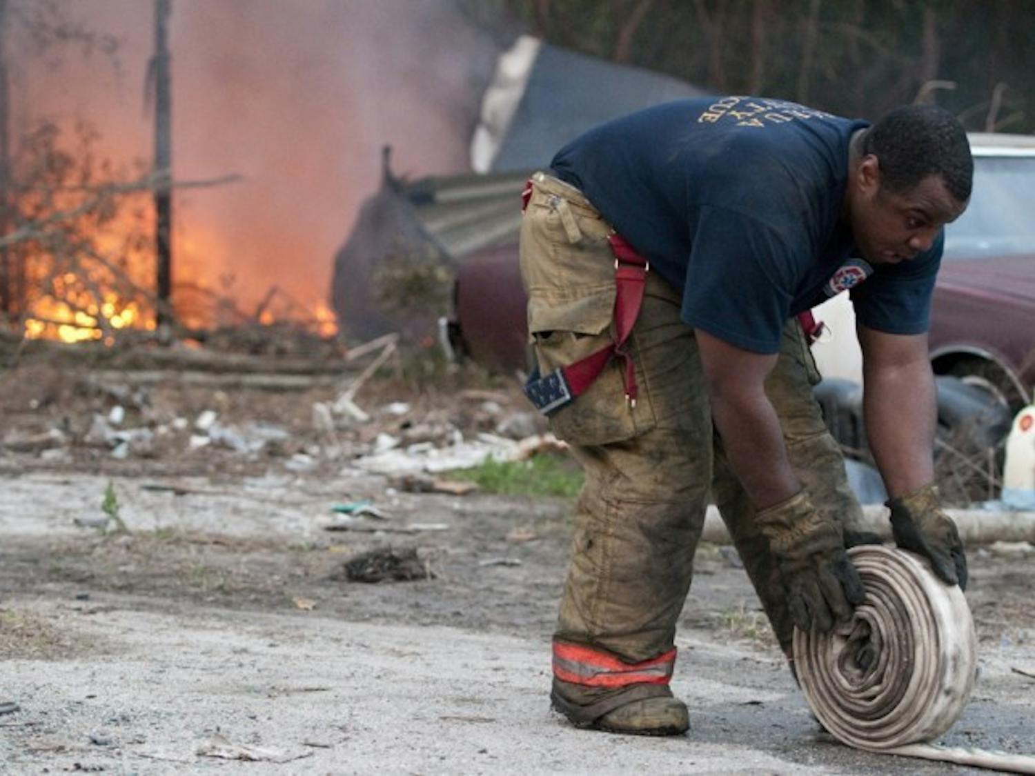 An Alachua County Fire Rescue Worker packs up equipment at 3530 SE Hawthorne Road after tending to a commercial tire fire Tuesday evening.