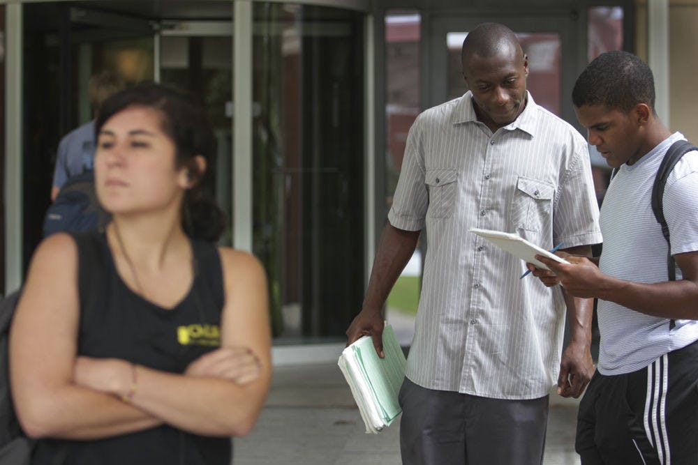 <p>A pedestrian, left, declines to talk to paid petition circulator Terry Williams, center, while 19-year-old UF biology sophomore Alex Fethiere signs a petition to put the "Rights of Electricity Consumers Regarding Solar Energy Choice" amendment to Forida's constitution on the ballot. Fethiere said he signed the petition because the amendment could help citizens get cleaner energy.</p>