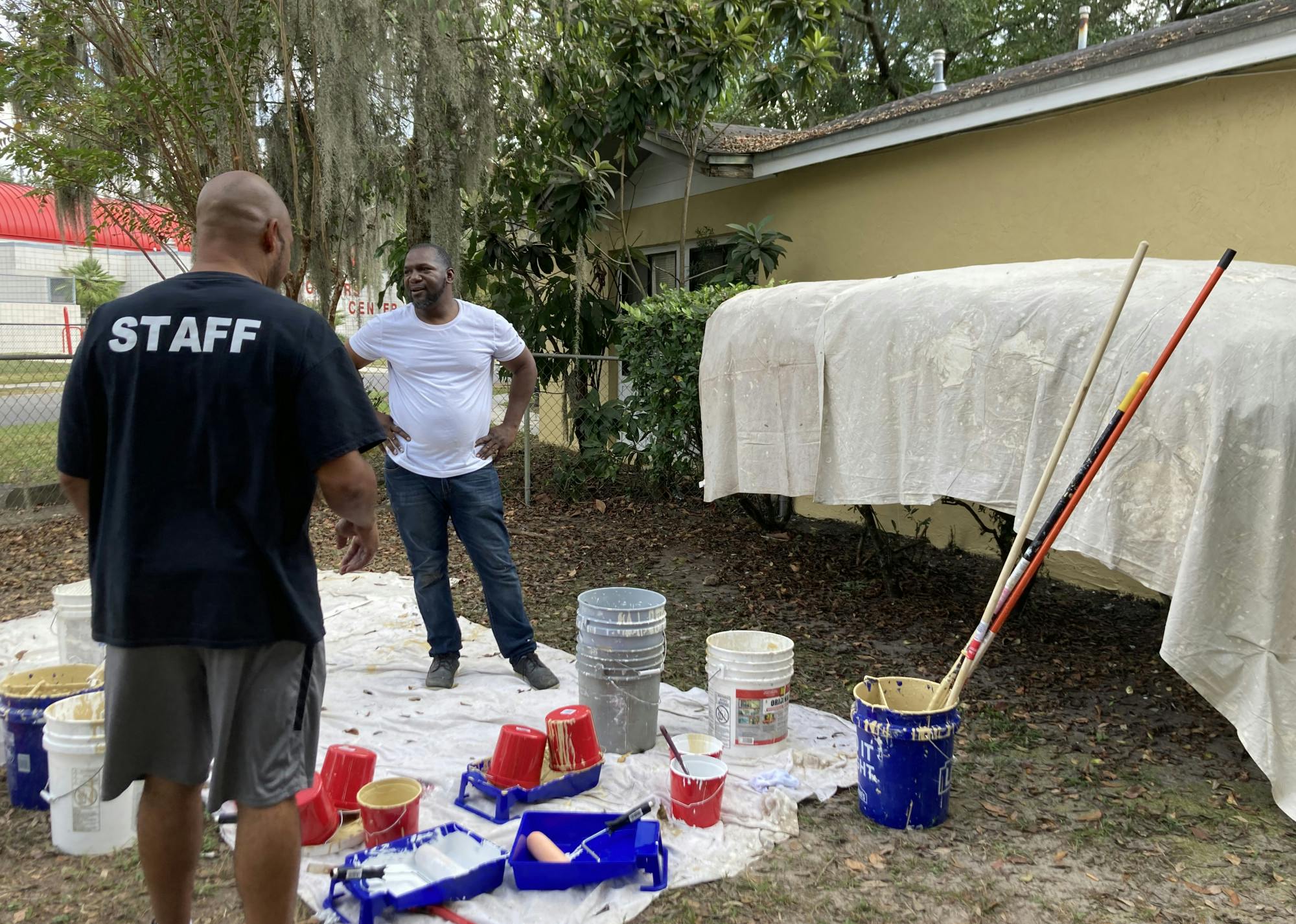 Rev. Ron Rawls (left) and Rev. Gerard Duncan (right) stand next to Ruby Williams’ house after painting it a bright yellow on Saturday, Oct. 16, 2021.