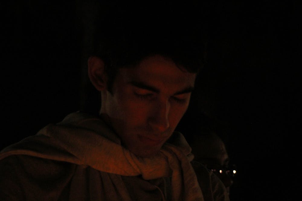 Damon Ghetmiri, a 22-year-old UF mechanical engineering senior, lights a candle during a vigil for those who died in Iran and Iraq. There was a 7.3 magnitude Sunday, which killed at least 450 people.